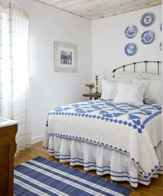 The bleached beadboard ceiling, iron bed, and blue-and-white color scheme of this bedroom fit the cottage style of this seaside home. | Photo: Laura Moss