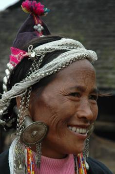 China | Wa woman wearing traditional earrings.  These earrings are hollow, and women going to the market could unscrew the back of these earrings and place their rolled up their banknotes (money) into them. | Photographer unknown