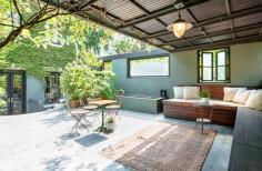 A landscaped roof deck features a waterfall, irrigated planters, and a trellis covering of ivy over a built-in seating area.