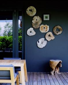 Patio space with wood slab slices hung on a blue wall.