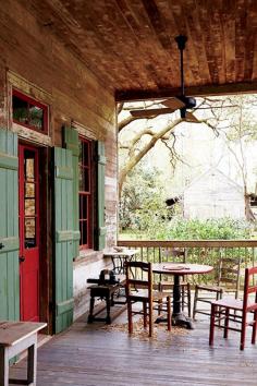 Step Inside the Ultimate Bayou Cottage | DomaineHome.com // Southern front porch with wooden chairs and green barn doors.