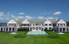 An all white South Hampton mansion with black shutters on a beautiful well-manicured lawn.