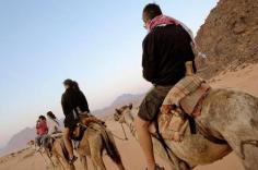 Tourists camel riding in the dry valley of Wadi Rum, Jordan